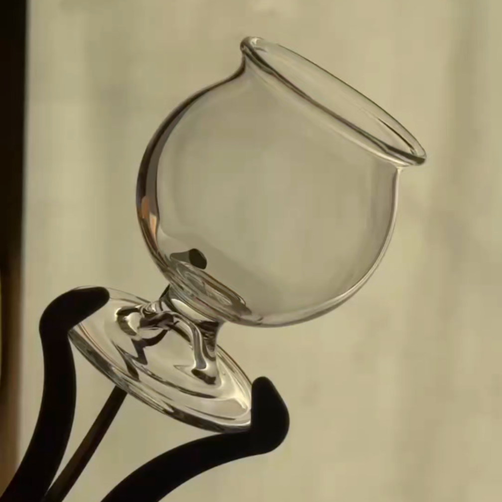 Clear brandy glass being held by a glassblowing tool at its stem